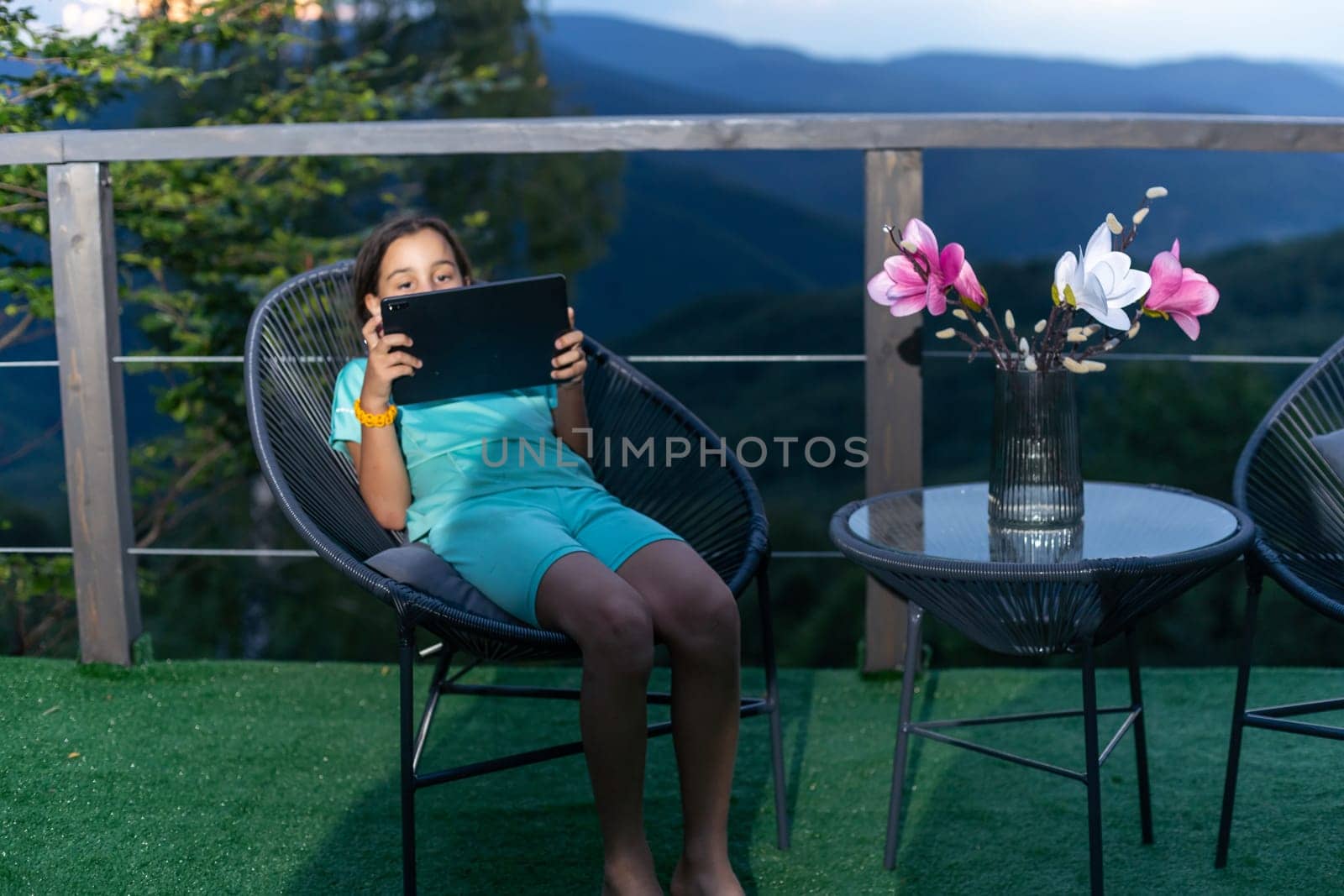 Little girl uses a tablet on the terrace by Andelov13