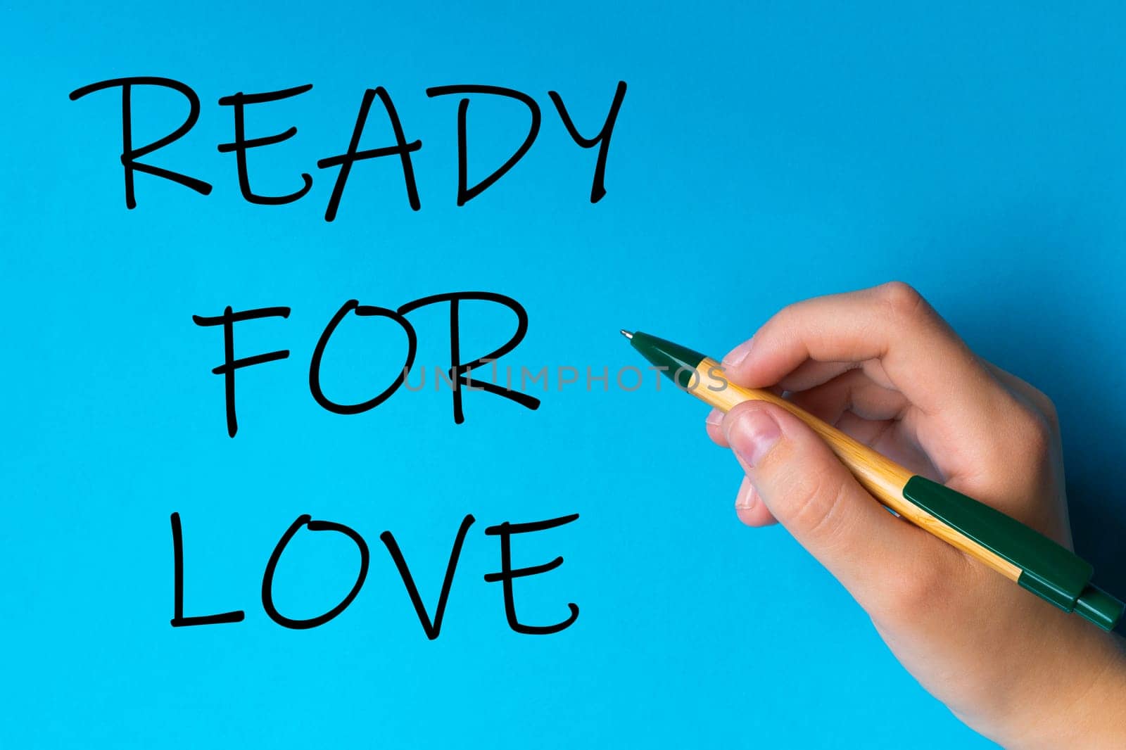 Children hand with pen write on a blue white background. Writing hand. Words Ready for love