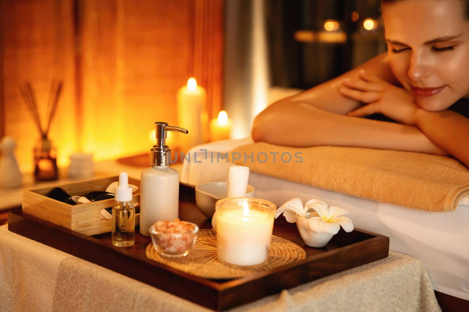 Caucasian woman customer enjoying relaxing anti-stress spa massage and pampering with beauty skin recreation leisure in warm candle lighting ambient salon spa at luxury resort or hotel. Quiescent