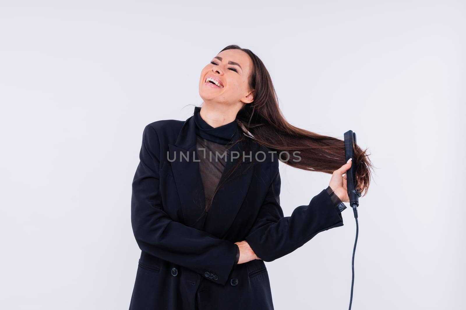 Happy young woman with beautiful hair holding curling iron on grey and red background by Zelenin