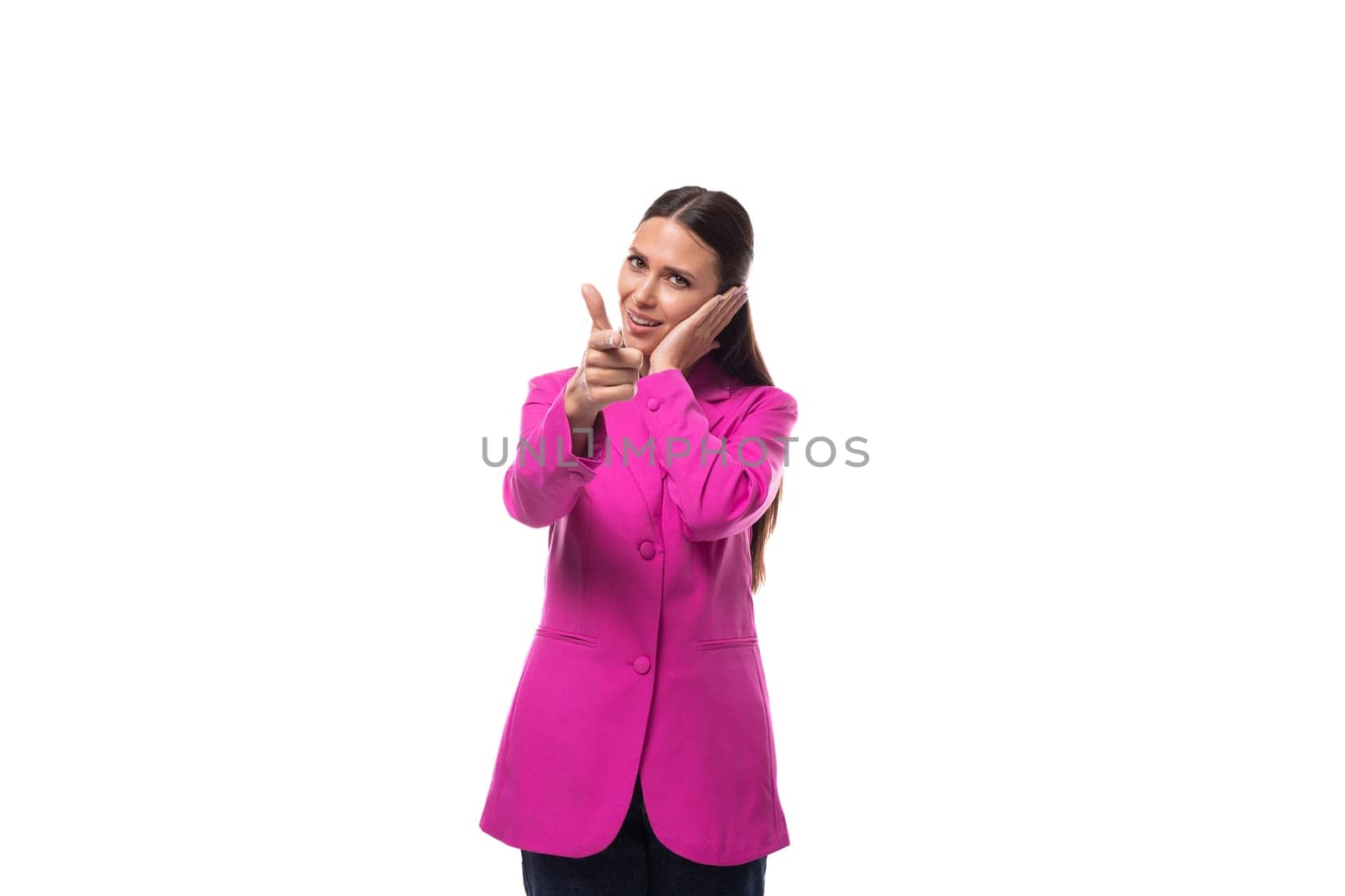 young boss woman dressed in a pink jacket stands thoughtfully on a white background.