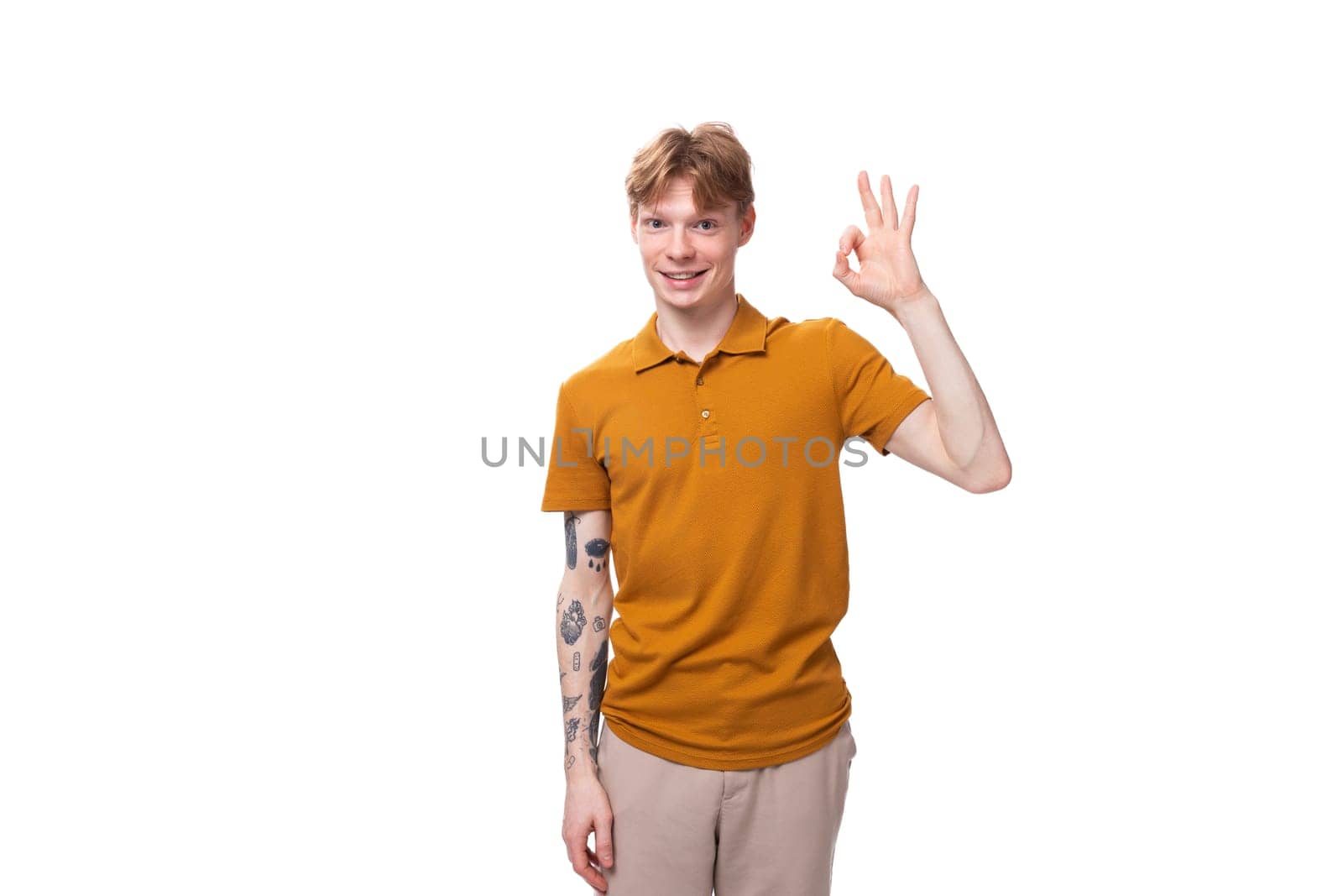 young stylish red-haired man with a haircut and a tattoo on his arm is dressed in a yellow t-shirt by TRMK
