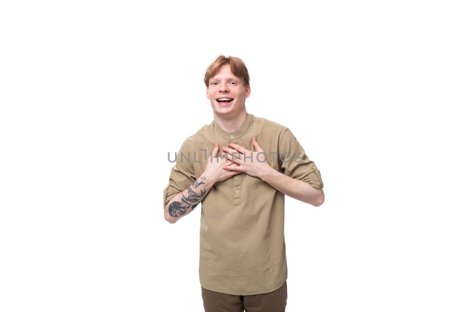 young emotional European man with red golden hair is dressed in a light brown shirt on a white background.