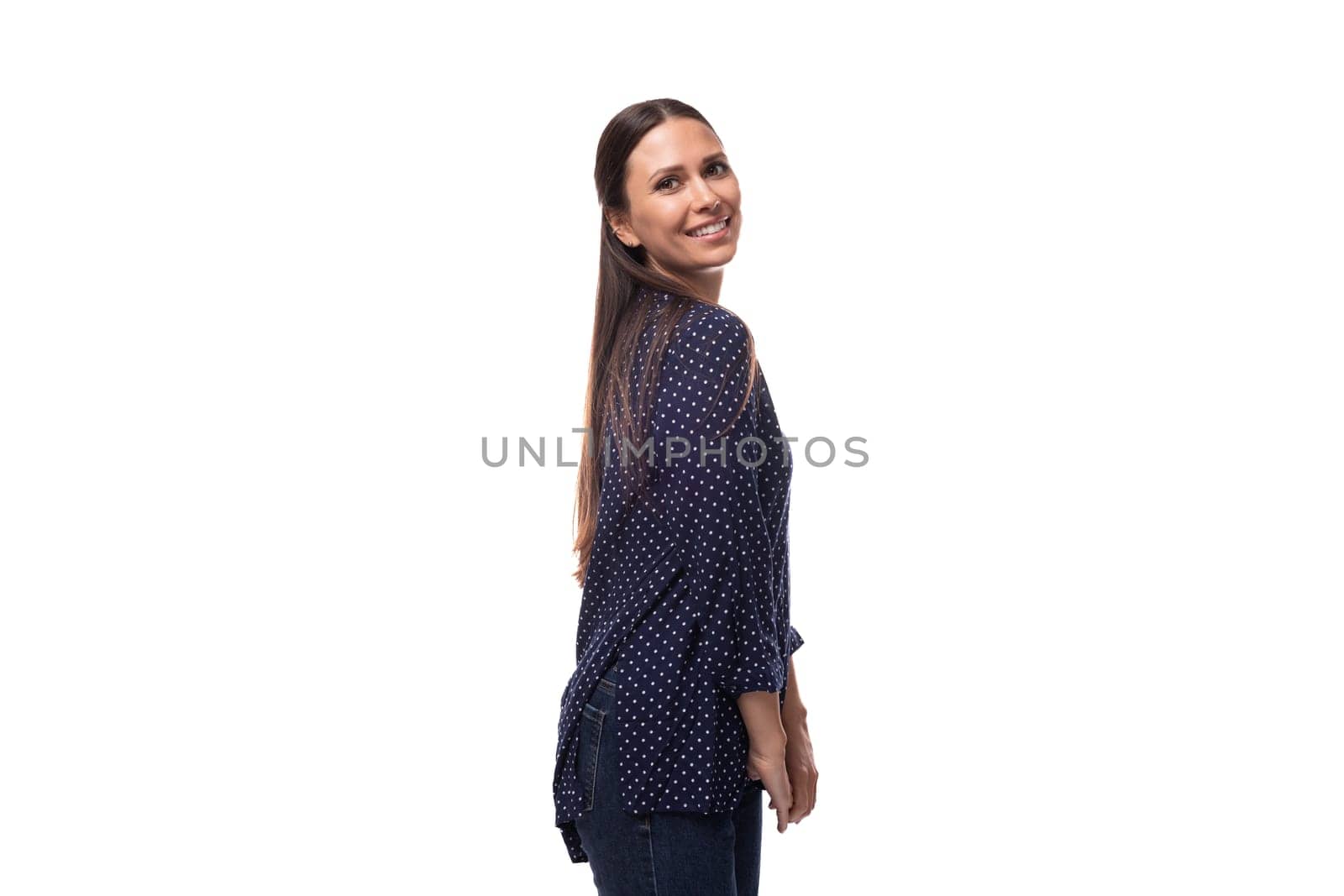 young brunette advertiser woman dressed in a blue blouse with a polka dot pattern looks happy and joyful on a white background with copy space by TRMK