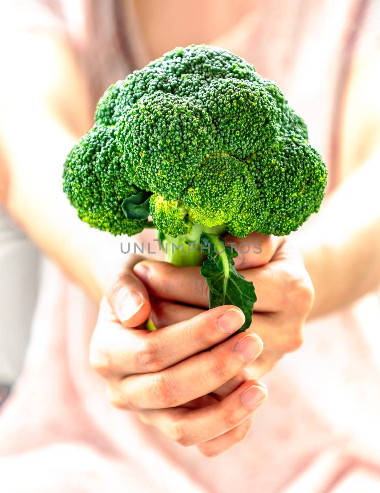 The lady is holding fresh green broccoli and giving it to the camera. Healthy eating concept, Space for text, Selective focus.