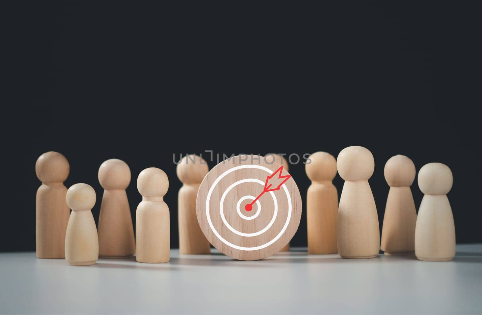 Target concept of business and personnel in a company. wooden dolls standing around Dart board and arrows for creating and targeting business objectives. Marketing solutions, targets for business investment.