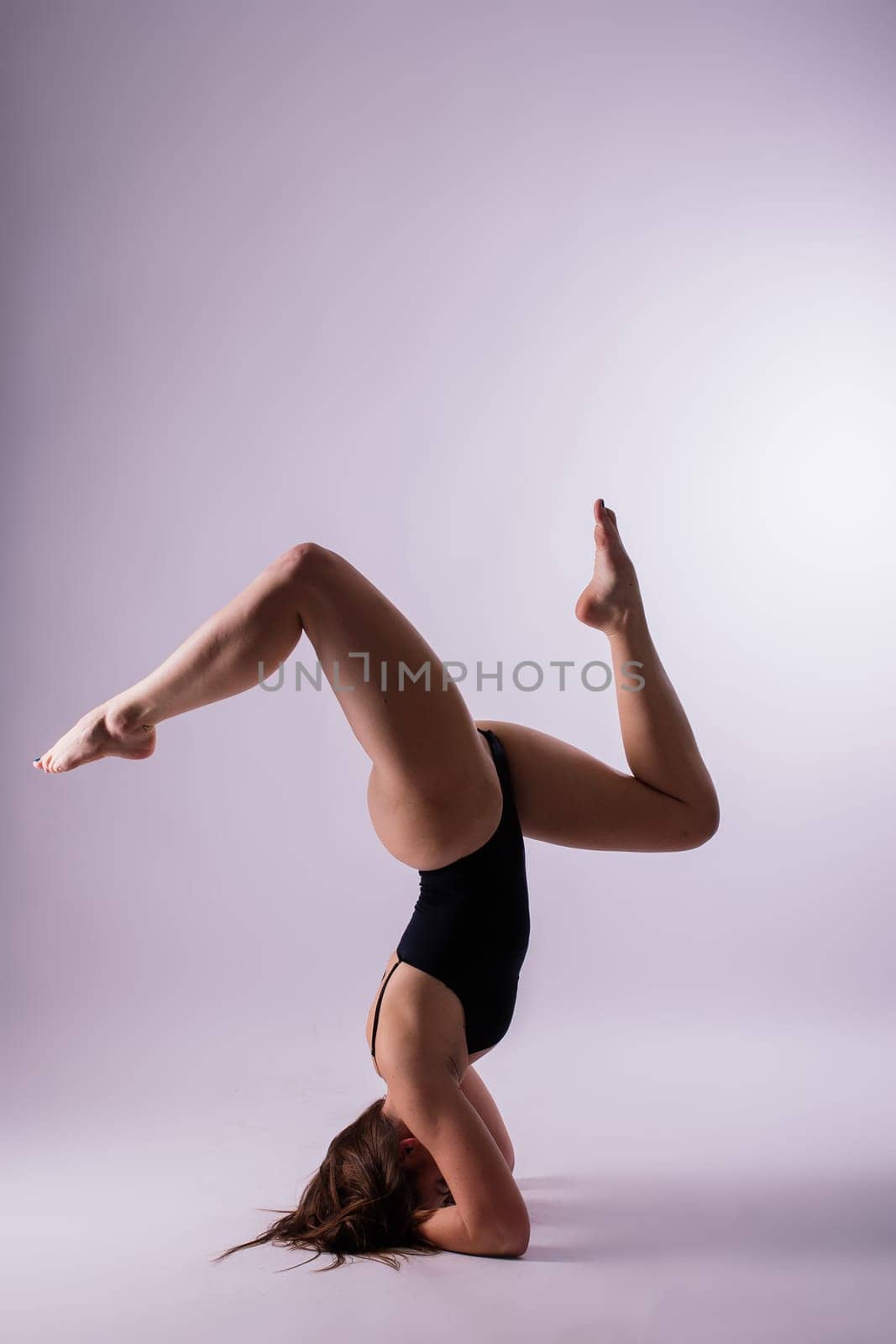 Side view of a beautiful slim young woman working out, doing yoga or pilates exercise. Full length