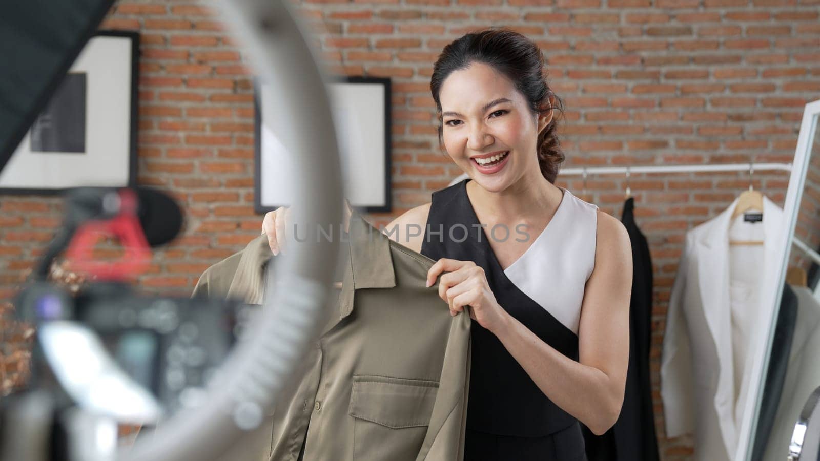 Woman influencer shoot live streaming vlog video review clothes social media or blog. Happy young girl with apparel vivancy studio lighting for marketing recording session broadcasting online.