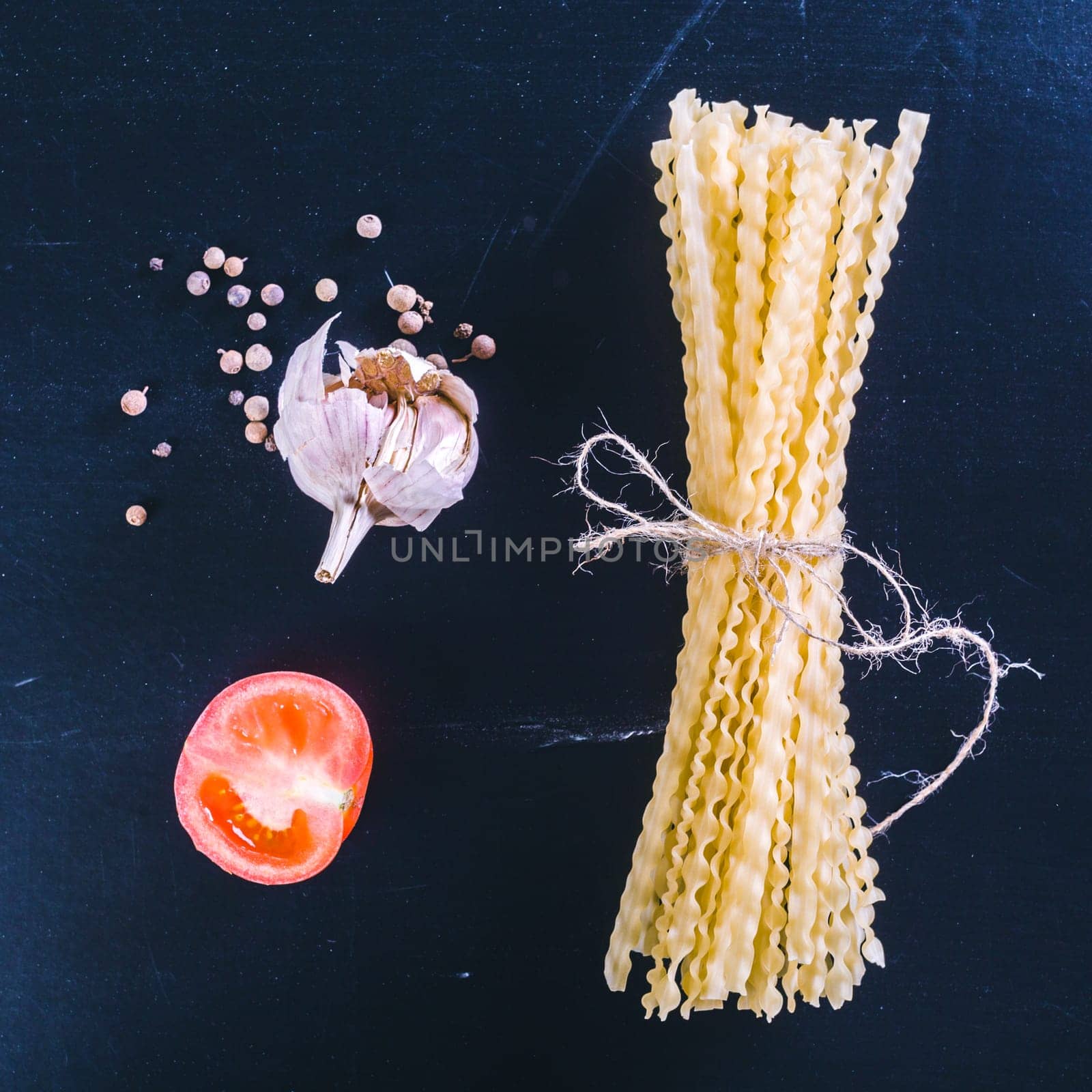 Raw spaghetti on black wooden background, top view