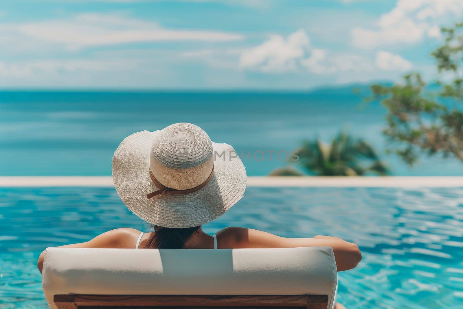 Fashionable woman in the back wearing a straw hat while on vacation at luxury poolside in resort.