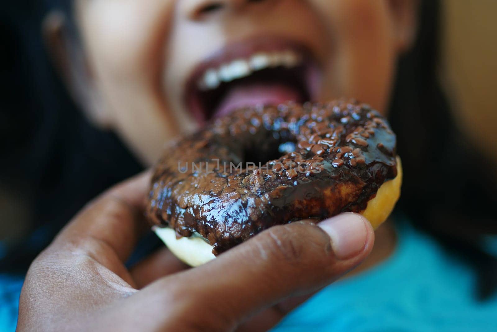 child mouth eating chocolate donuts .
