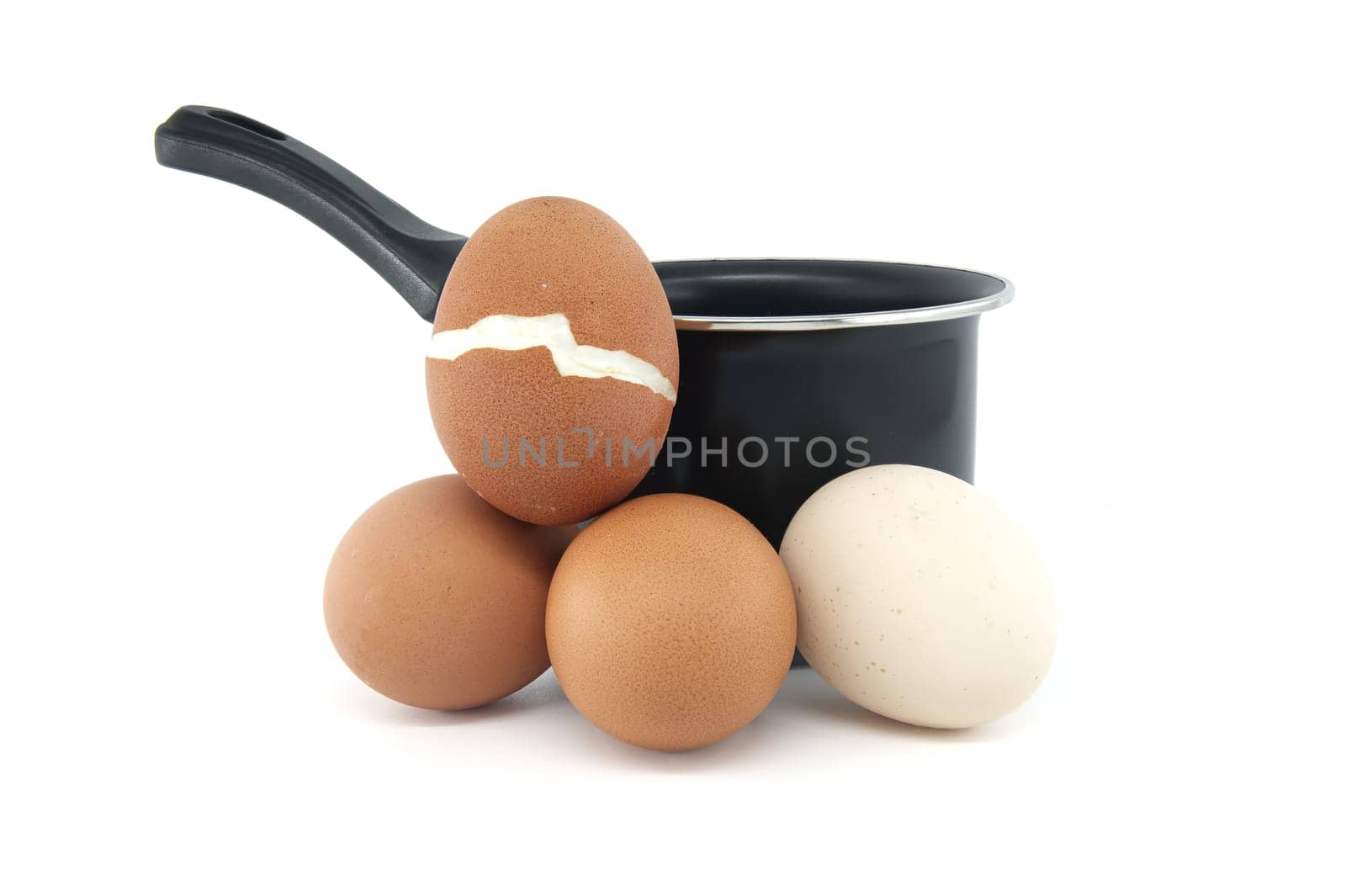 Isolated on a white background, a black cooking pot and group of hard-boiled eggs, one of which has broken during boiling