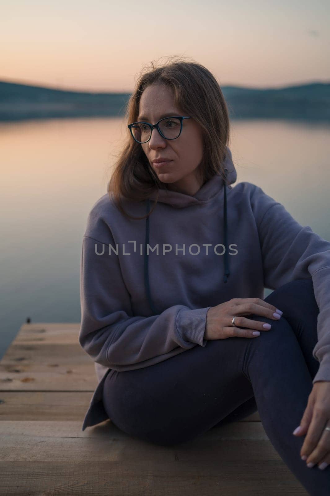 Woman sitting on the pier, closeup portrait, summer sunset