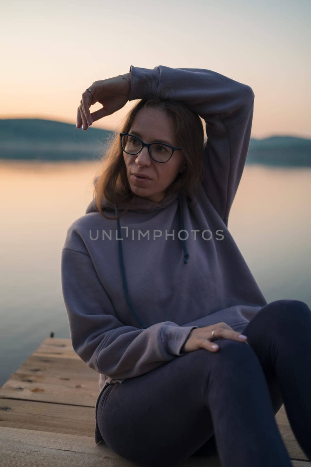 Woman sitting on the pier, closeup portrait, summer sunset