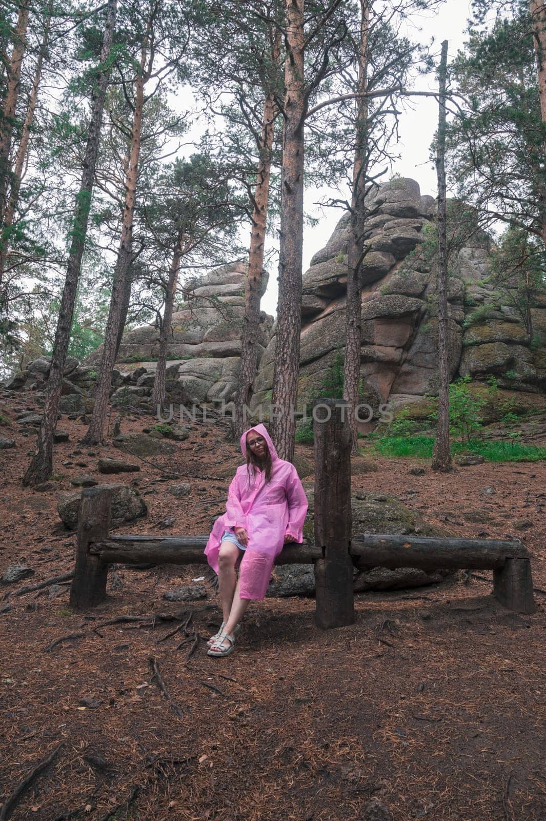 Woman in raincoat in the taiga forest and rocks of the Stolby nature reserve park, Krasnoyarsk, Russia