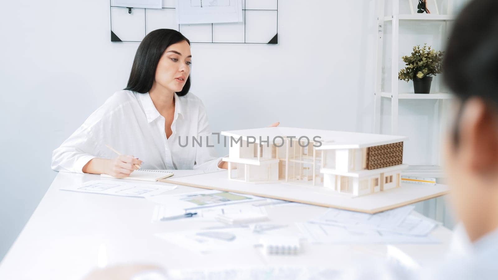 Professional asian male project manager hand puts the map on meeting table while discuss and brainstorm with coworker about building project at meeting room with blueprint hand behind. Immaculate.