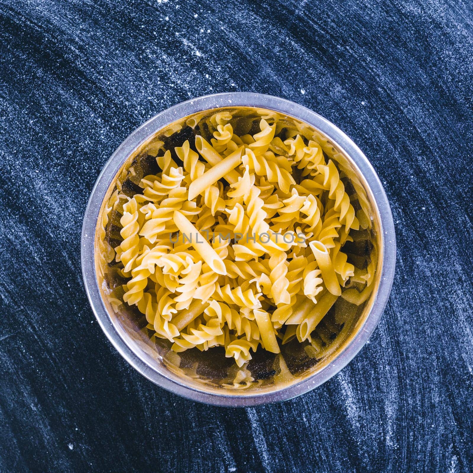 Raw spaghetti on black wooden background, top view
