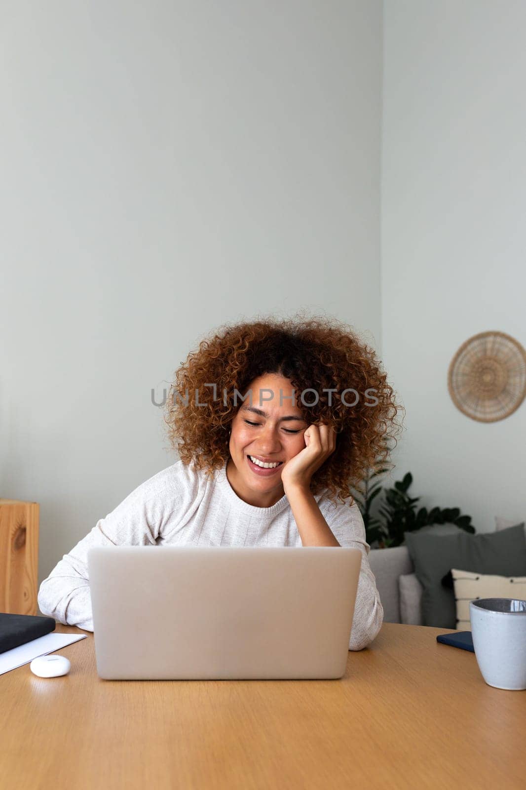 Vertical image of happy young african american woman working at home office. Happy multiracial hispanic female entrepreneur using laptop. Working at home concept.