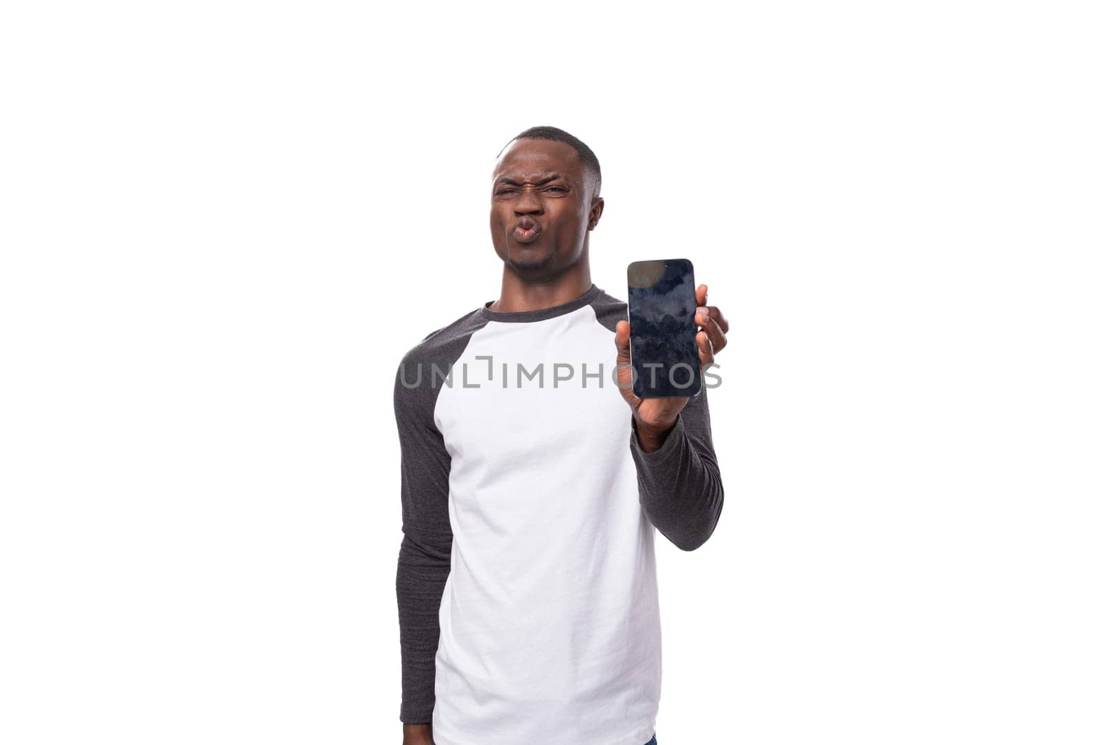 young handsome american man dressed in a long-sleeved sweater demonstrates the screen of a smartphone with a mockup.