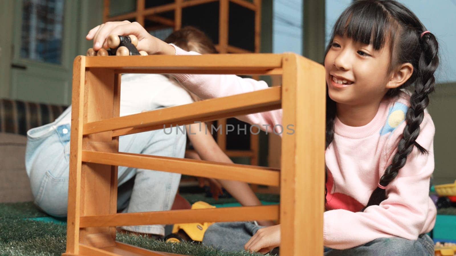 Closeup of cute asian girl play car toy with friend at play room. Diverse children using car model to improve imagination. Adorable children enjoy playing robotic model. Educational game. Erudition.