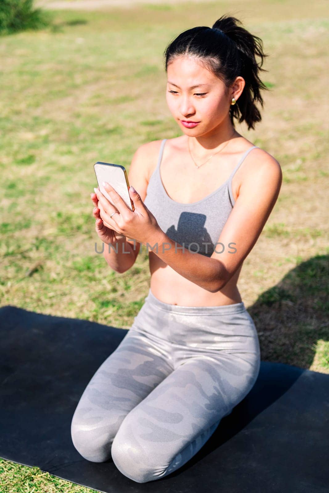 asian woman using mobile phone for a yoga session by raulmelldo
