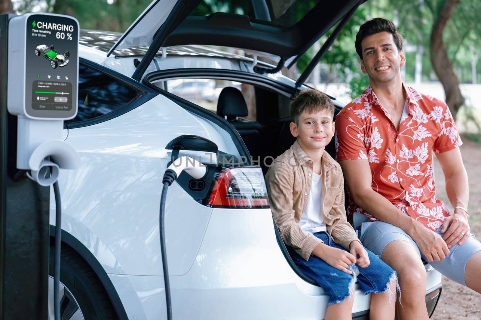 Family road trip vacation with electric vehicle, father and son recharge EV car with green and clean energy. Nature and travel with eco-friendly car for sustainable environment. Perpetual