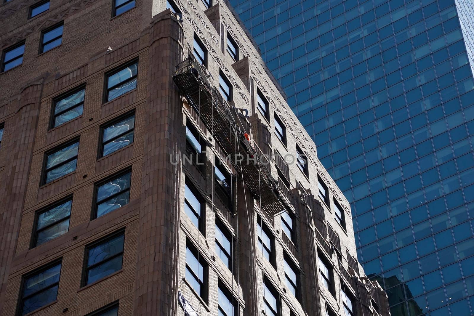 new york manhattan skyscrapers view from the street to the top of the building on sunny clear day by AndreaIzzotti