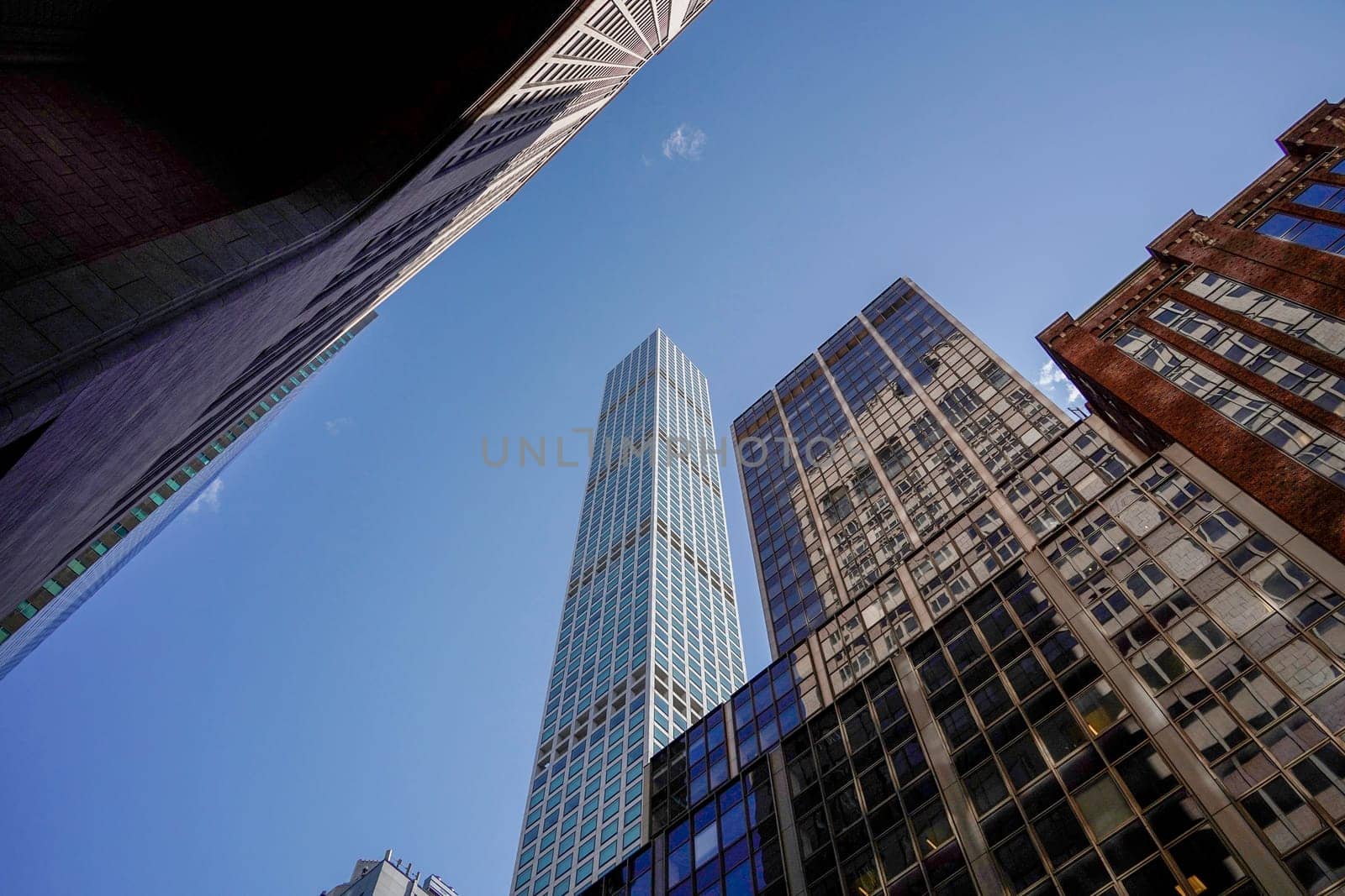 new york manhattan skyscrapers view from the street to the top of the building on sunny clear day by AndreaIzzotti