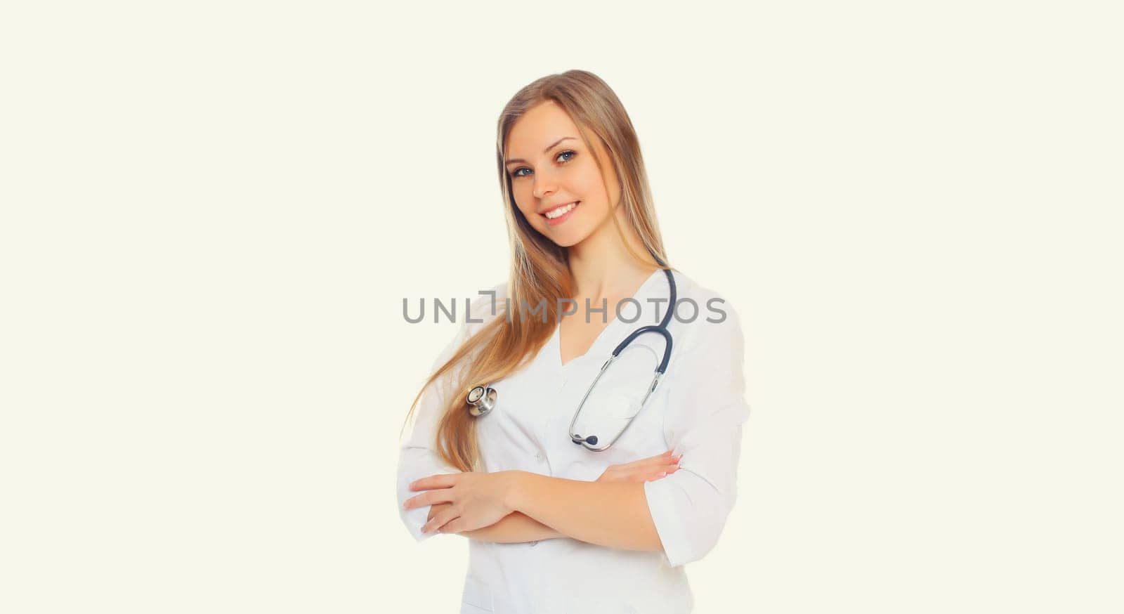 Portrait of happy friendly smiling young woman doctor with stethoscope and crossed arms posing on white studio background