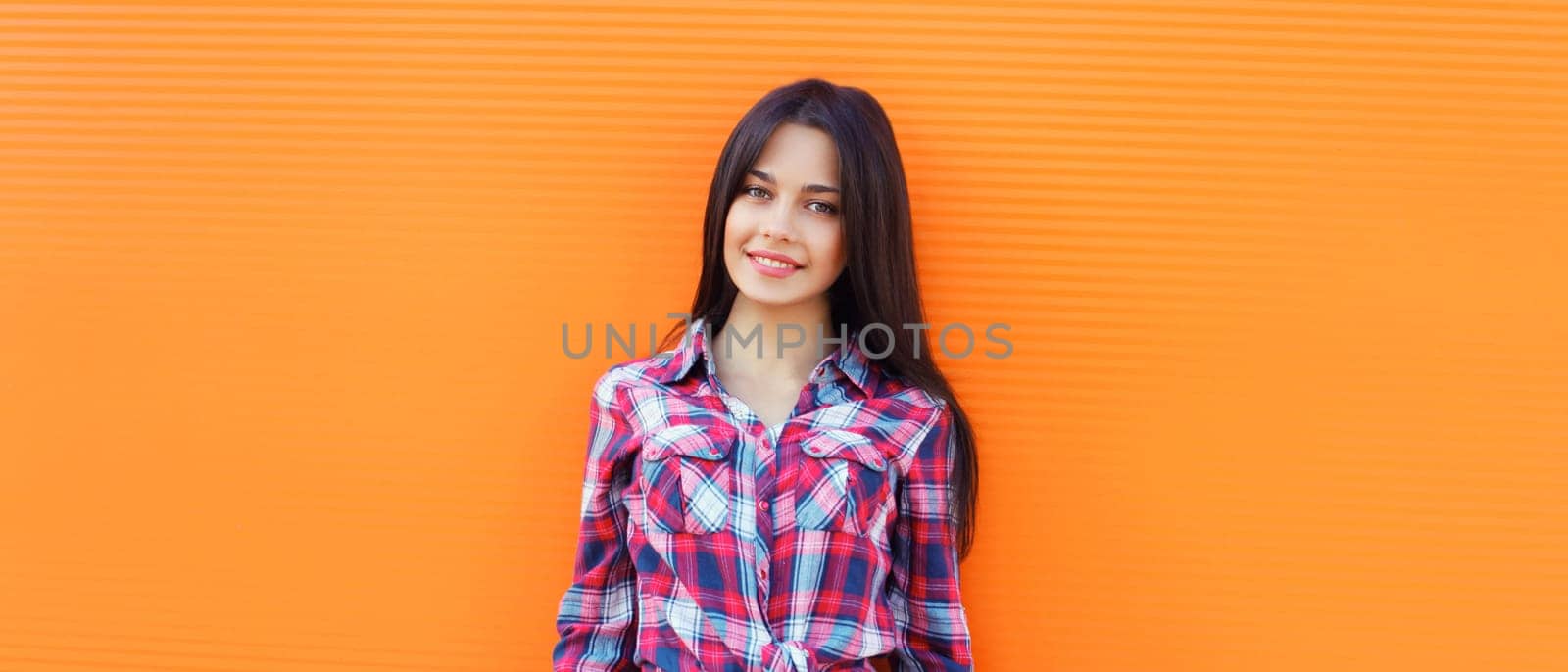 Portrait of happy smiling brunette young woman looking at camera posing on orange background