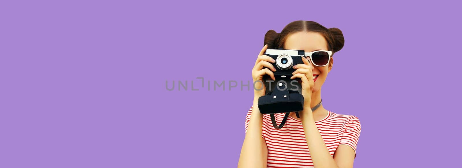 Portrait of happy young woman photographer with film camera, female on violet studio background, copy space for advertising text