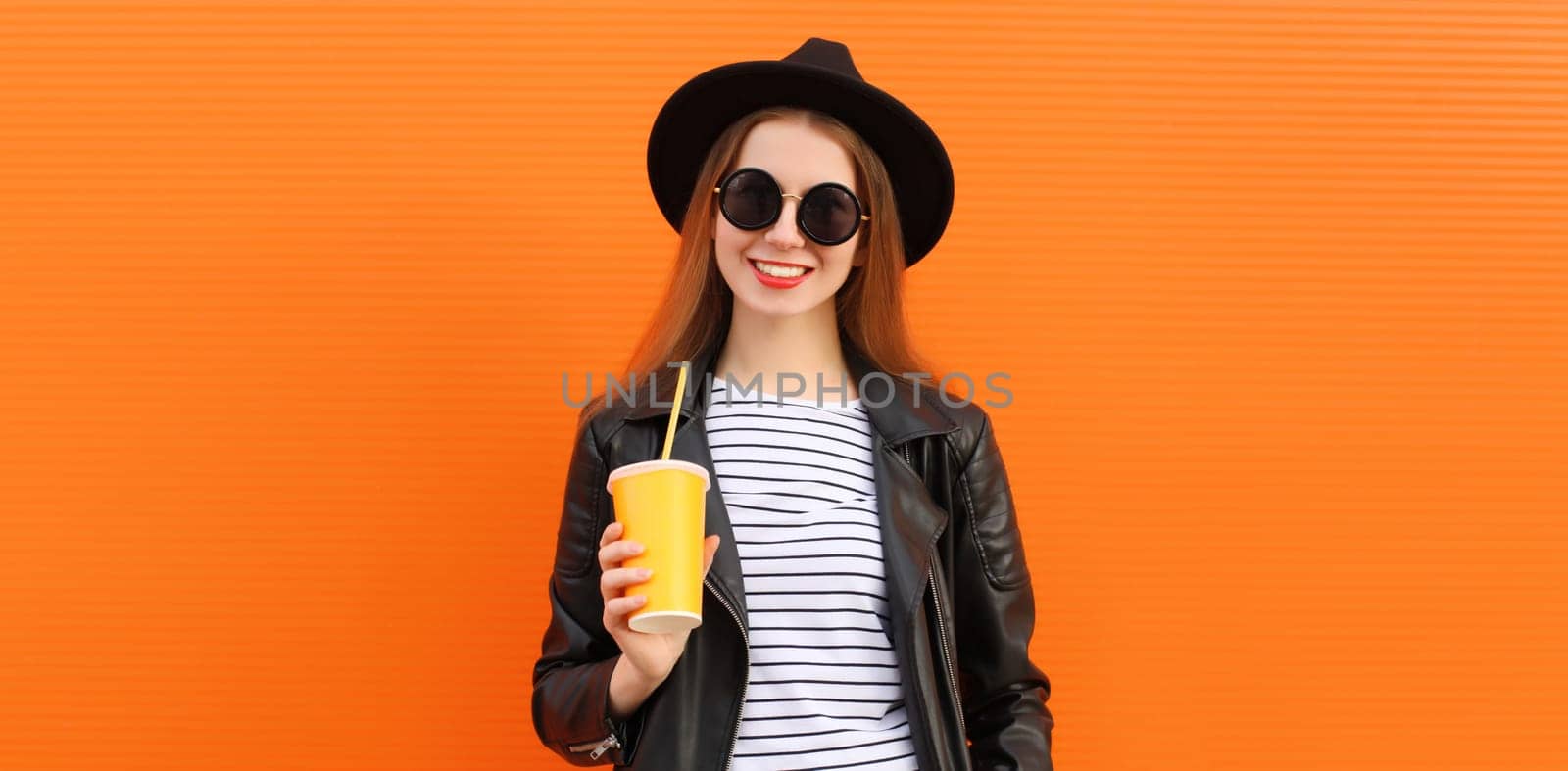 Portrait stylish young woman drinking juice posing in black rock style leather jacket, round hat by Rohappy