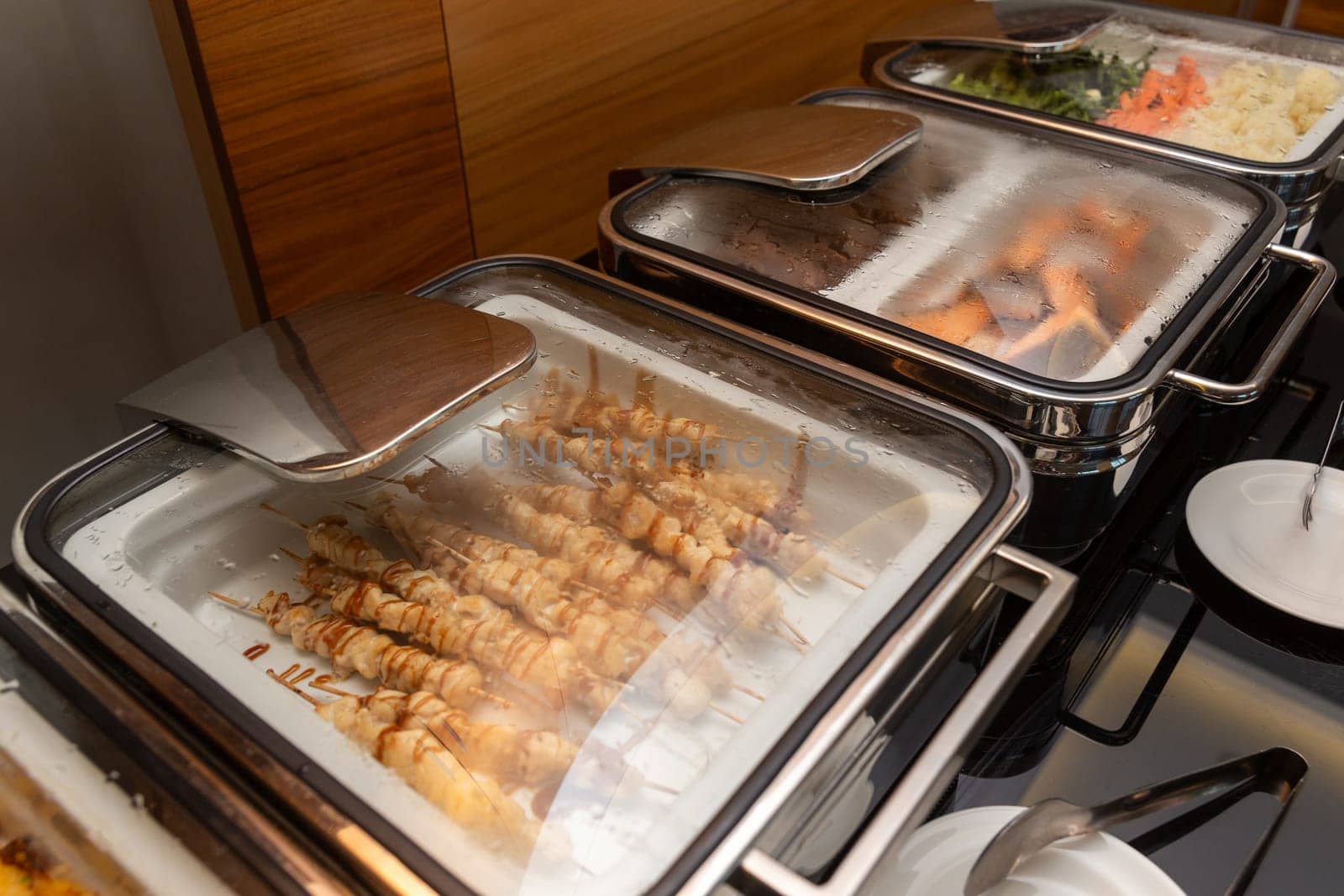 Fried meat on skewers and other appetizers in a food warmer on a buffet table in a hotel restaurant. by BY-_-BY