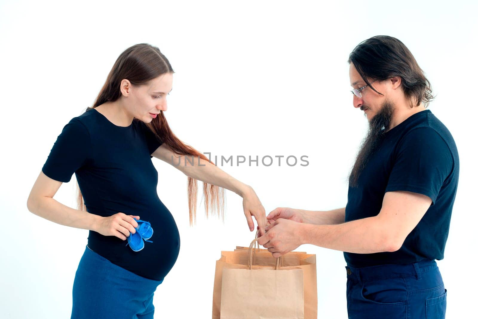 Portrait happy young pregnant woman and her husband with shopping bags and touching her big belly isolated on white background. Pregnancy shopping concept happy young family with shopping bags