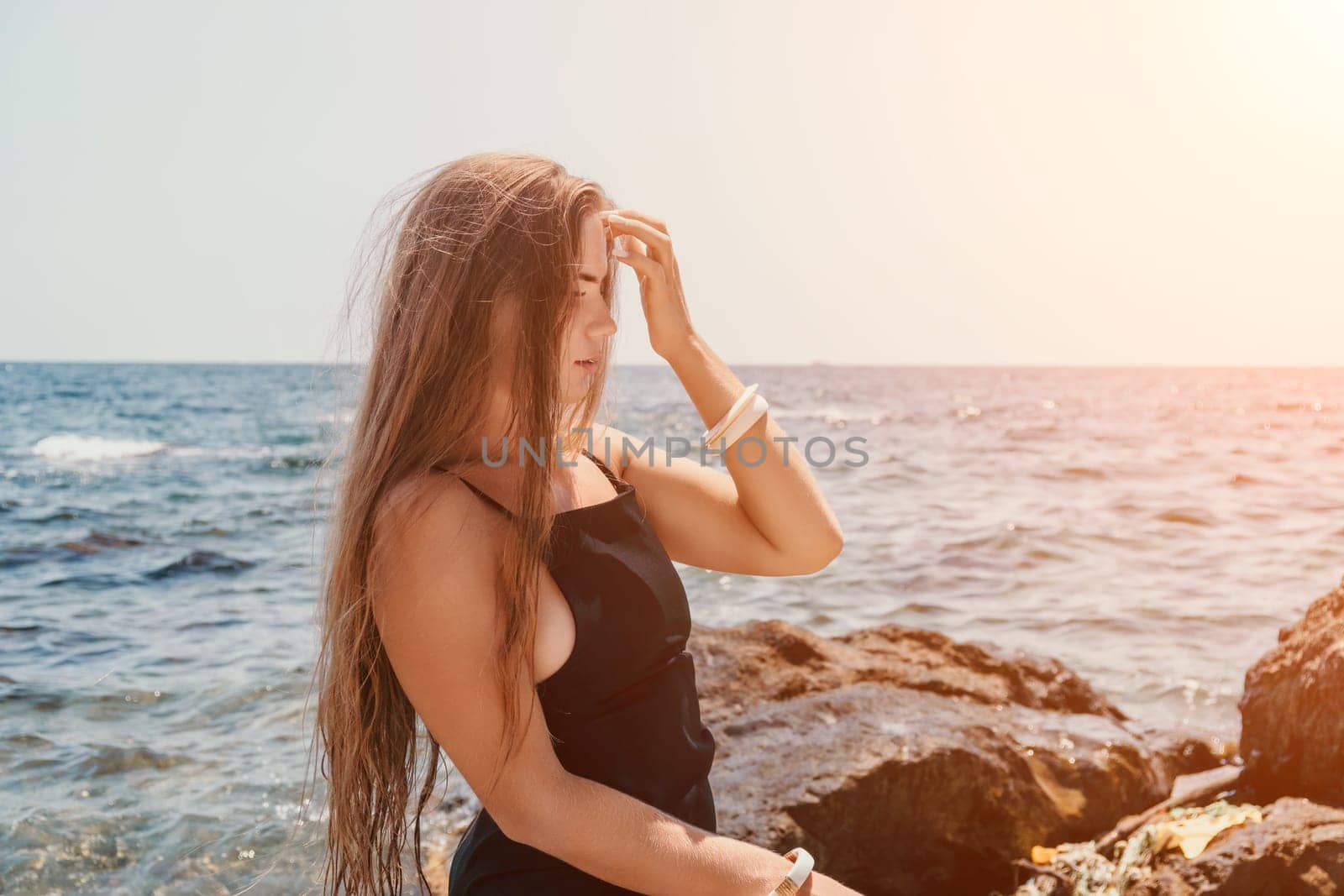 Woman travel sea. Young Happy woman in a long red dress posing on a beach near the sea on background of volcanic rocks, like in Iceland, sharing travel adventure journey