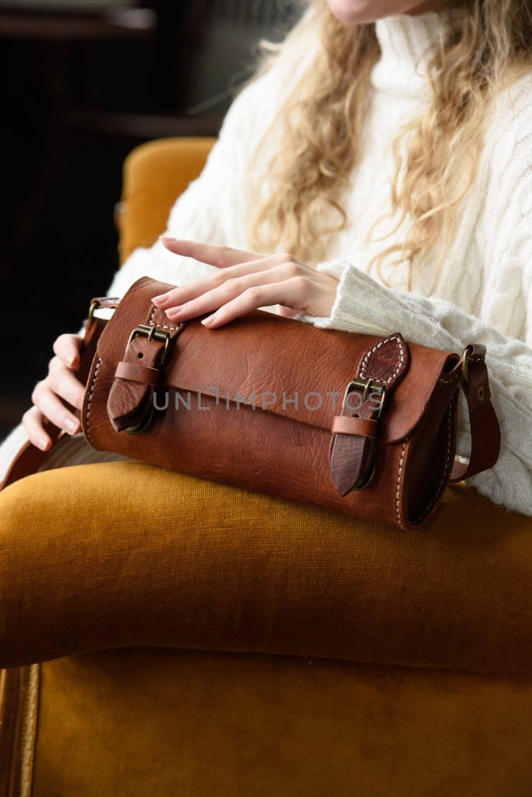 beautiful curly blond hair woman posing with a small tube brown bag in a vintage chair by Ashtray25