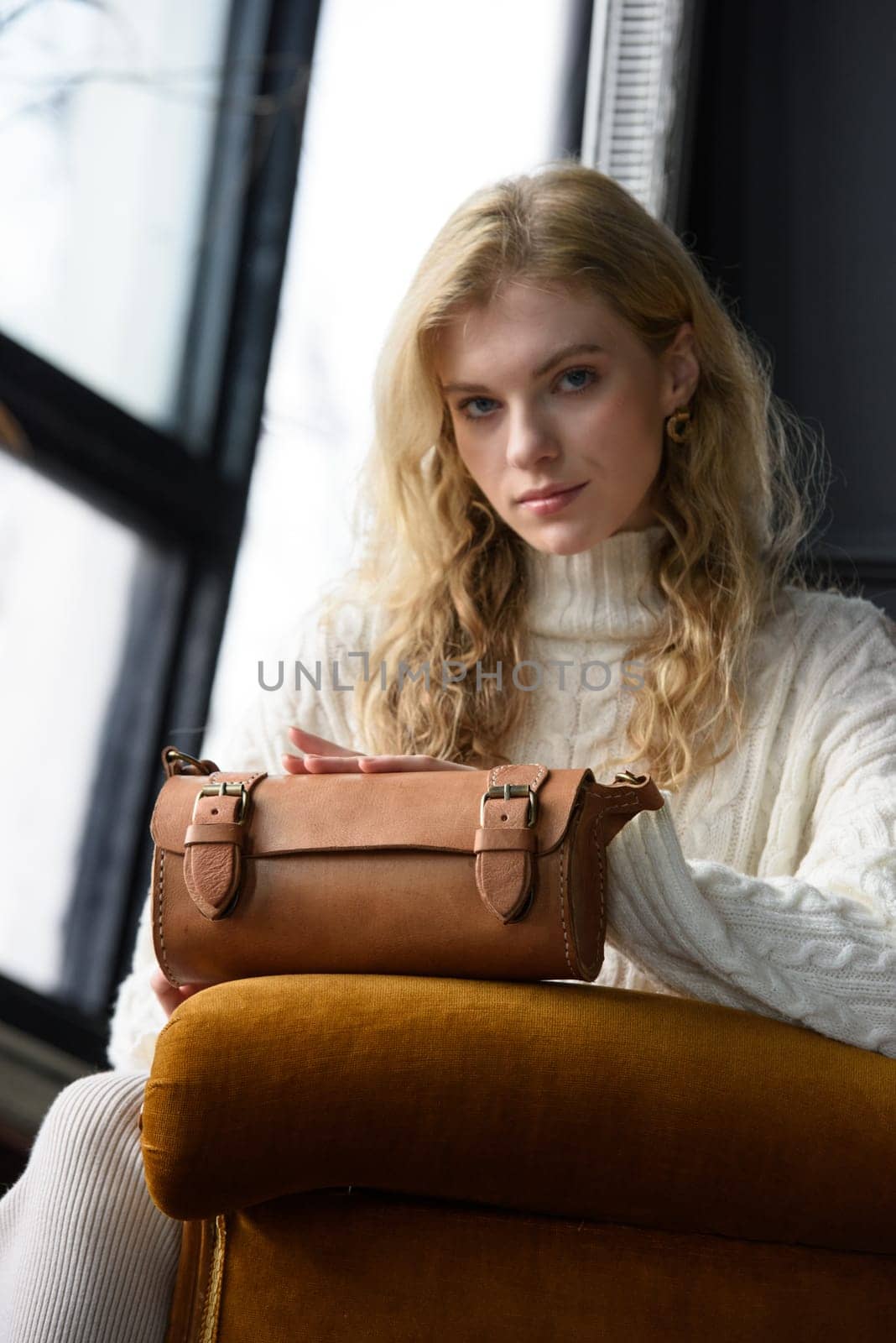 beautiful curly blond hair woman posing with a small tube brown bag in a vintage chair by Ashtray25