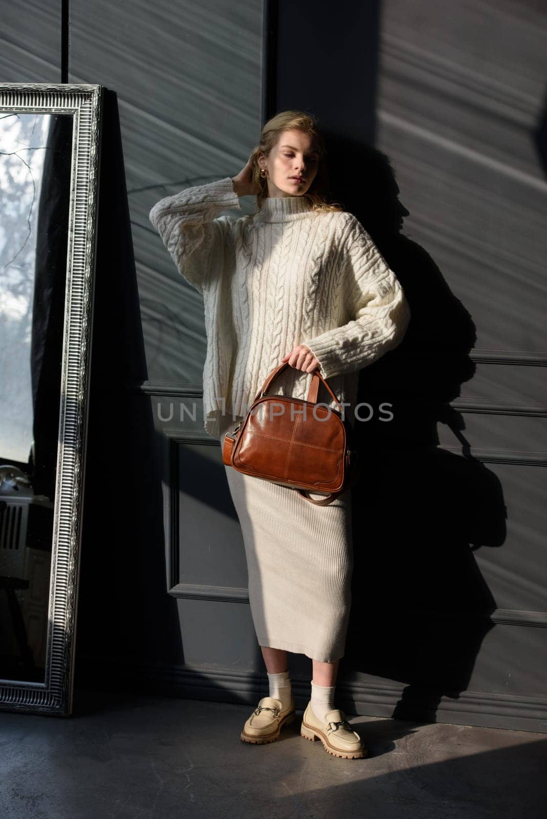 Studio portrait of beautiful woman with a curly blond hair holding brown bag, posing on gray background. by Ashtray25