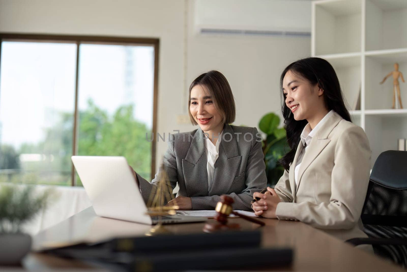 Lawyers woman and businesswoman discussing contract papers sitting at the table. Concepts of law, advice, legal service.