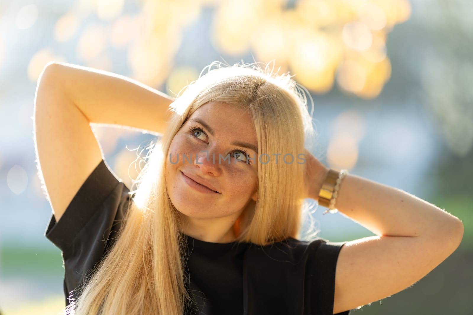 A young woman with blonde hair and braces is smiling as she poses for a picture in the park.