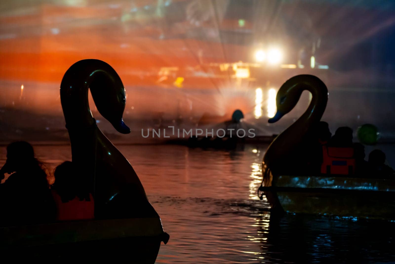 People in a swan shaped boat enjoying the light, sound and fountains show at Gadisar lake showing the famous tourist spot near Jodhpur and a place to relax by Shalinimathur