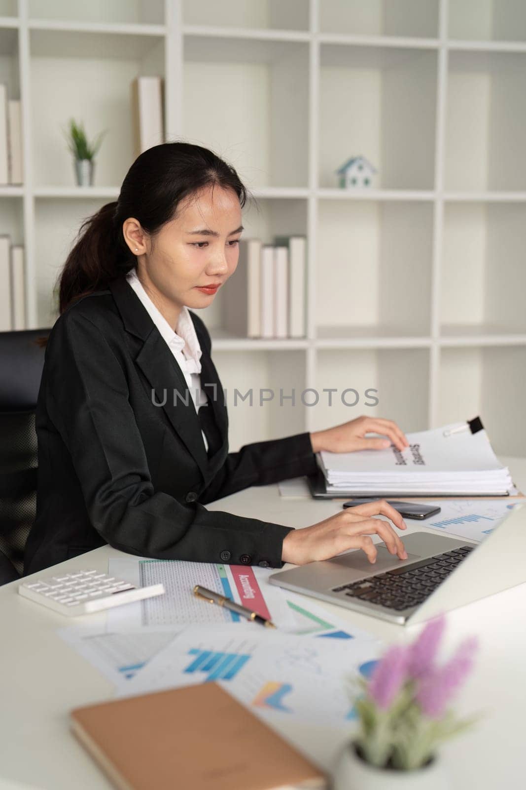 Young business woman asian or employee accounting bookkeeping documents checking financial data or marketing report working in office with laptop. Paperwork management.