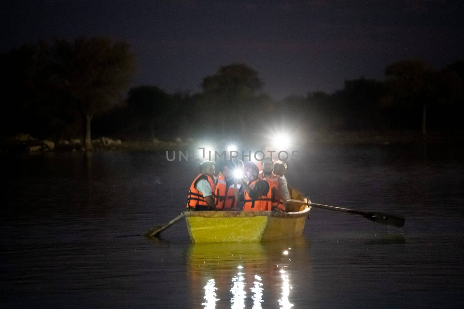 Jaisalmer, Rajasthan, India - 28th Dec 2023: People sitting in a boat on a dark lake flashing lights from their phones and enjoying the music relaxing, waiting for rescue, celebrating on Gadisar lake Jaisalmer Jodhpur