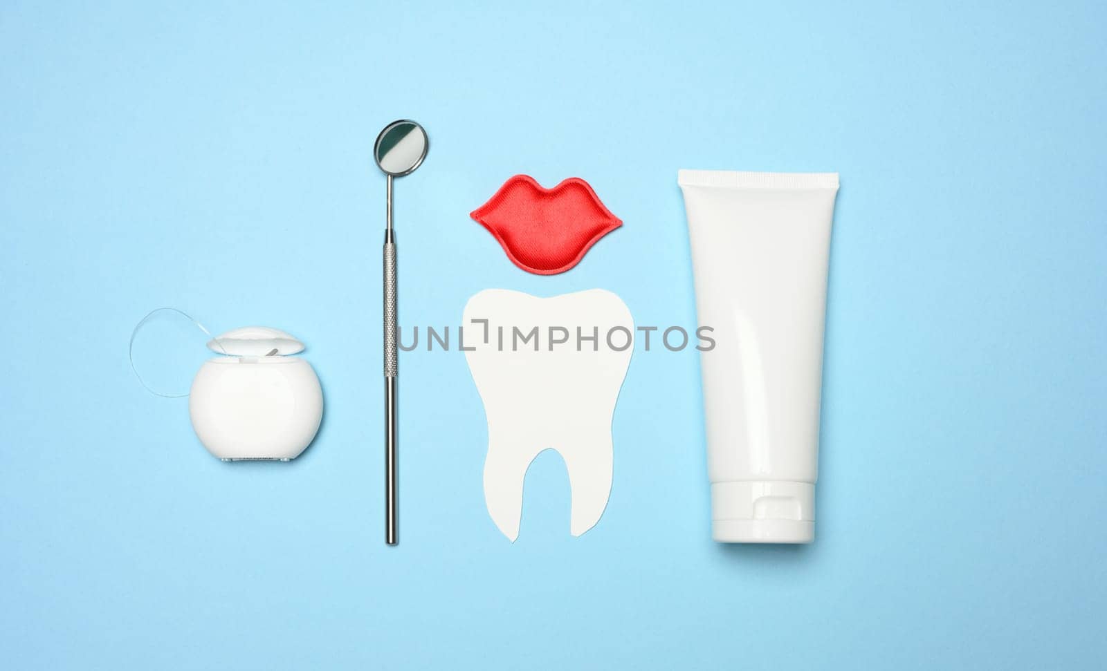 Tube with toothpaste, dental floss and dentist mirror on blue background by ndanko