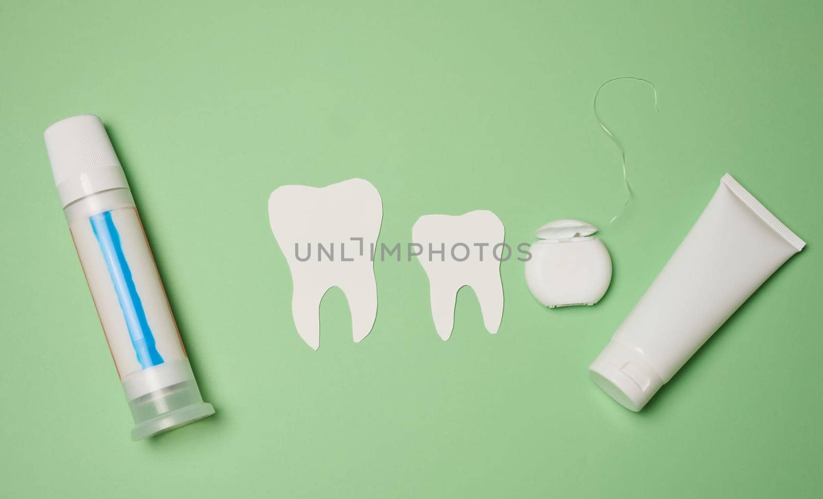 Toothpaste and dental floss on a green background, top view.  by ndanko