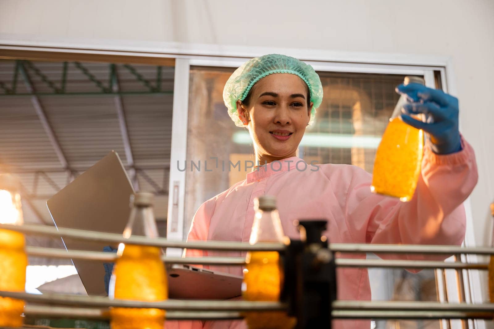 Quality inspector a woman carefully examines beverage bottles on a conveyor by Sorapop