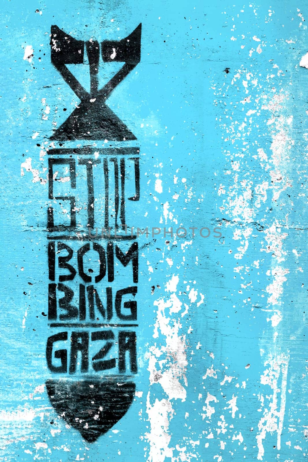 Graffiti on the vintage blue wall depicting the silhouette of a bomb. Inside message: STOP BOMBING GAZA. Copy space. Fully editable.