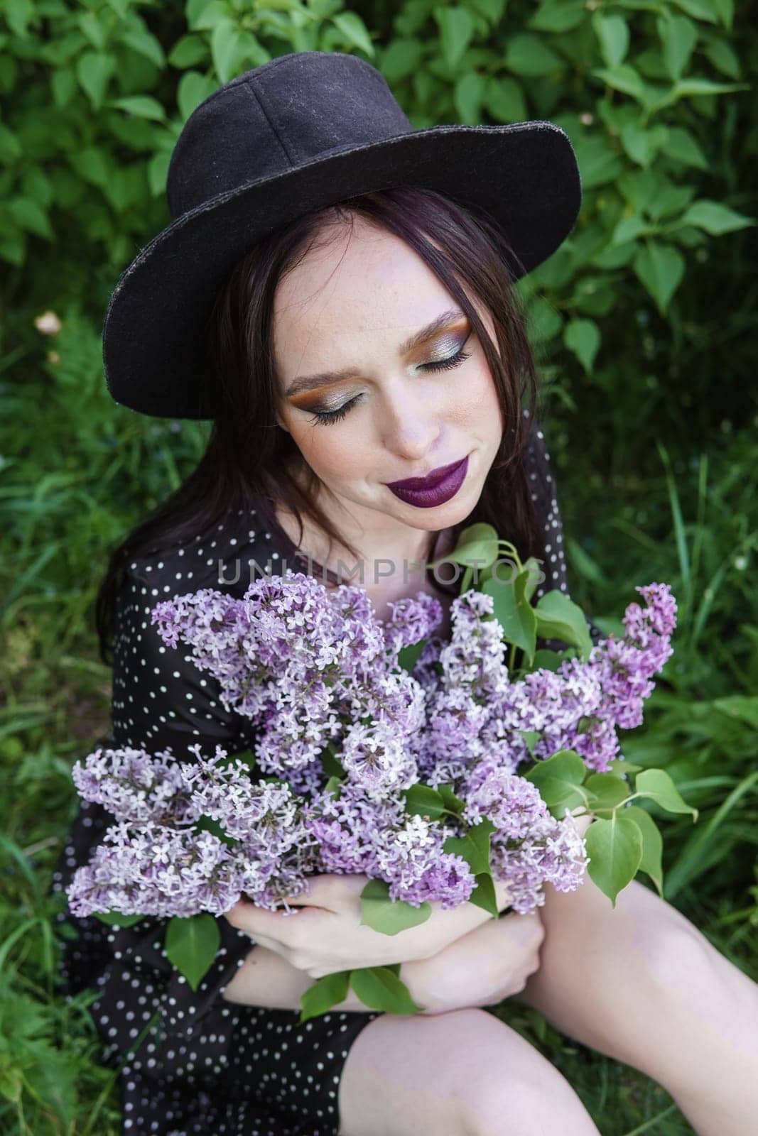 A fashionable girl with dark hair, a spring portrait in lilac tones in summer. Bright professional makeup