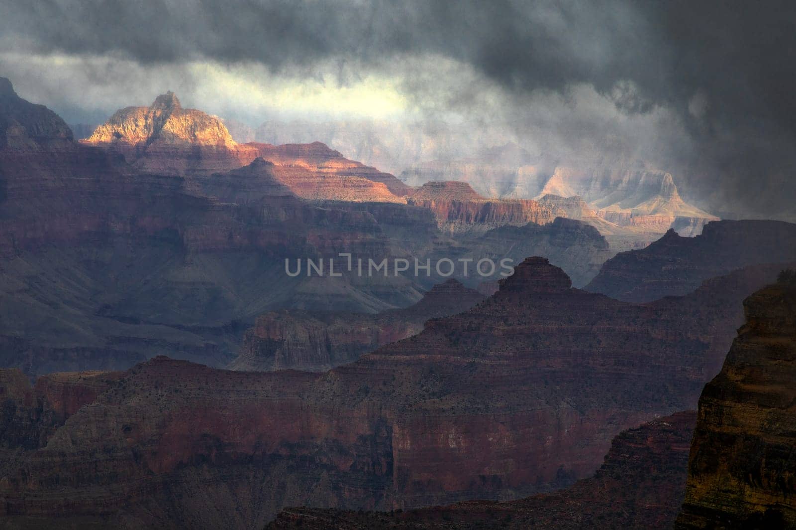 Passing rain storm produces clouds that filter the sunlight at Grand Canyon National Park, Arizona