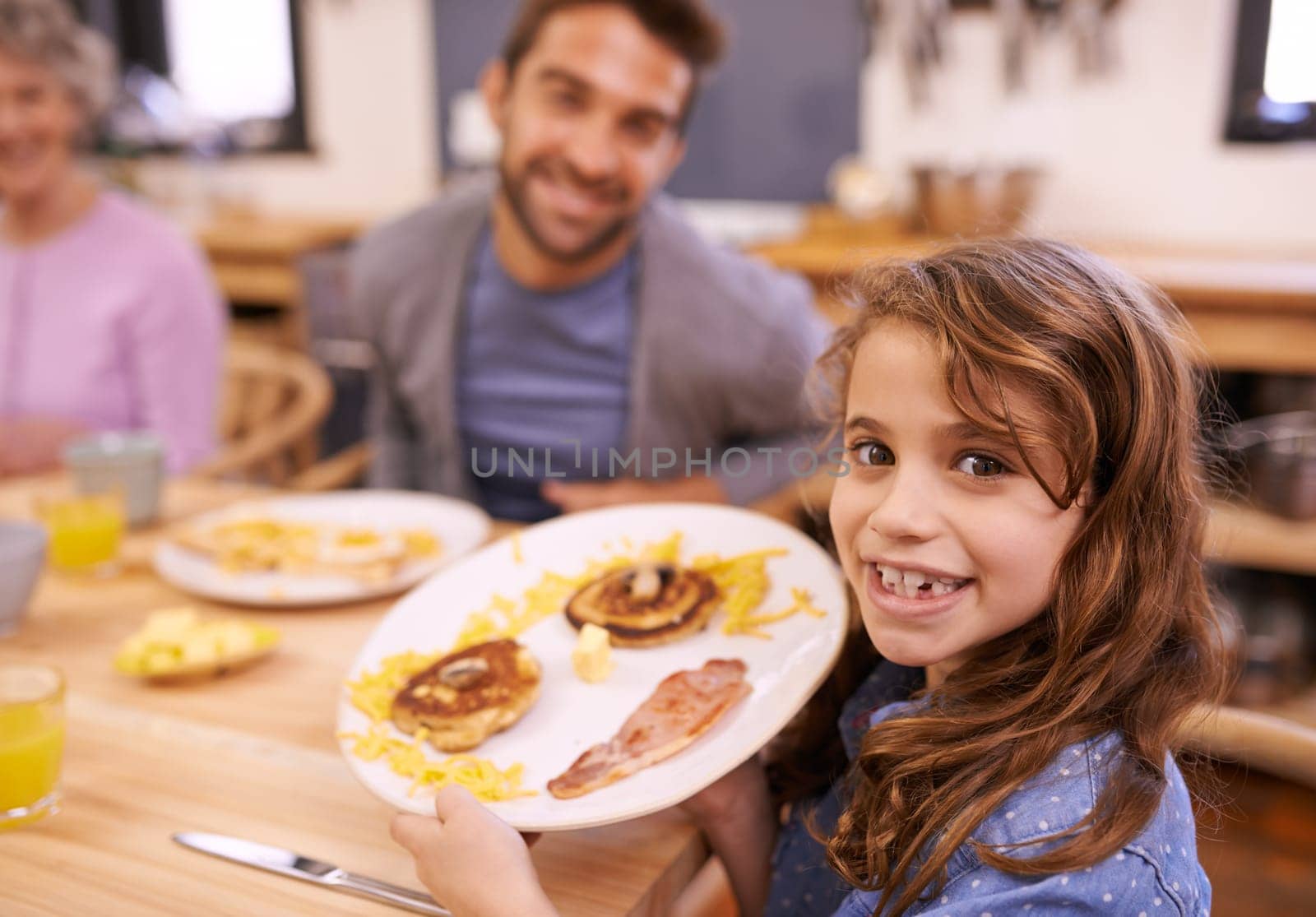 Portrait, child and breakfast in kitchen in home with family, eating and bonding together at table. Food, pancakes and father or grandmother with waffle for brunch nutrition or communication at house.